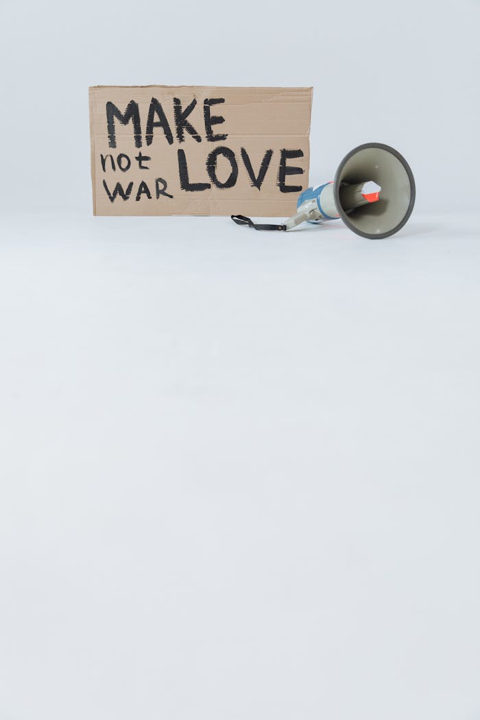 A cardboard sign saying 'Make Love Not War' with a megaphone on a white surface.